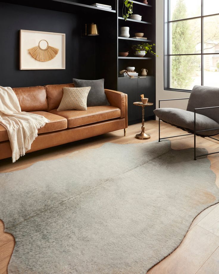 a living room filled with furniture and a rug on top of a hard wood floor