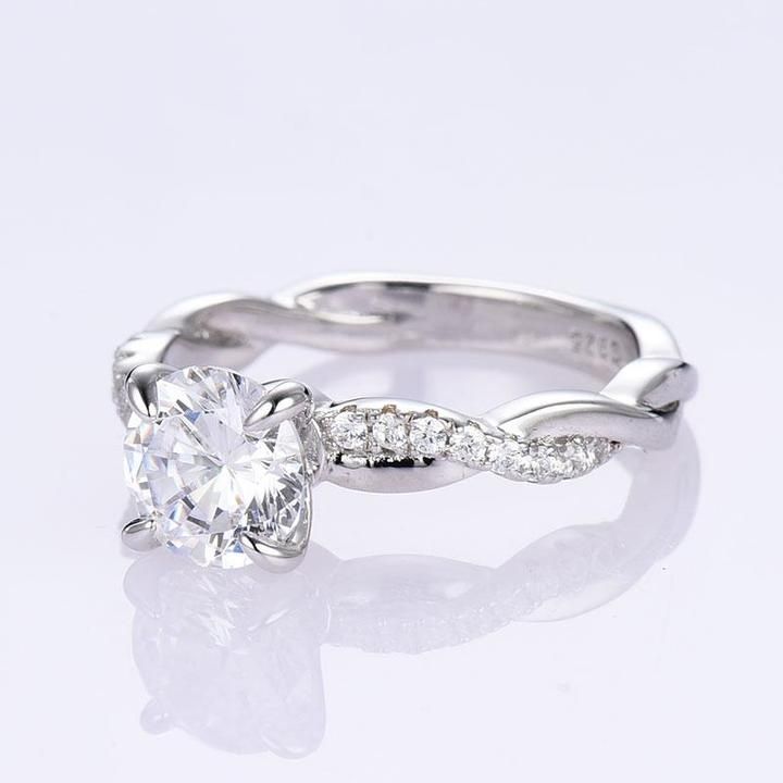 a white gold engagement ring with an oval cut diamond in the center and side stones on each band