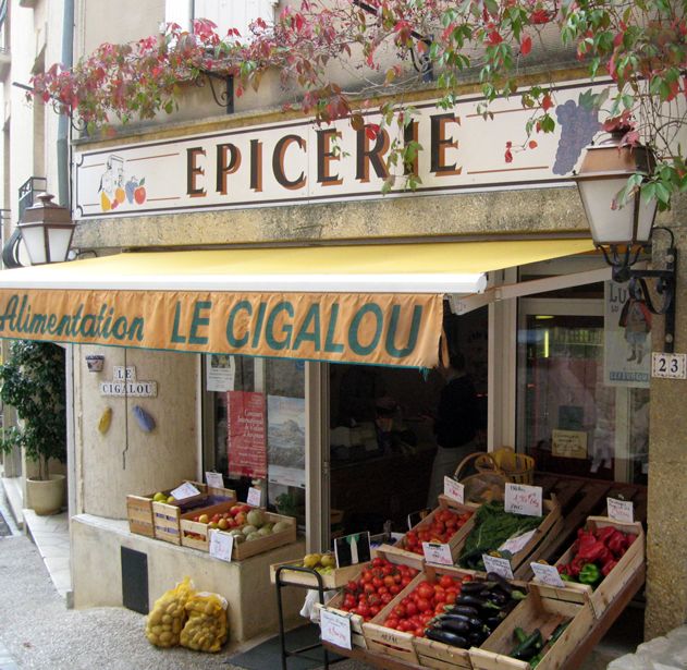 an outdoor market with fruits and vegetables on display in front of the store's window