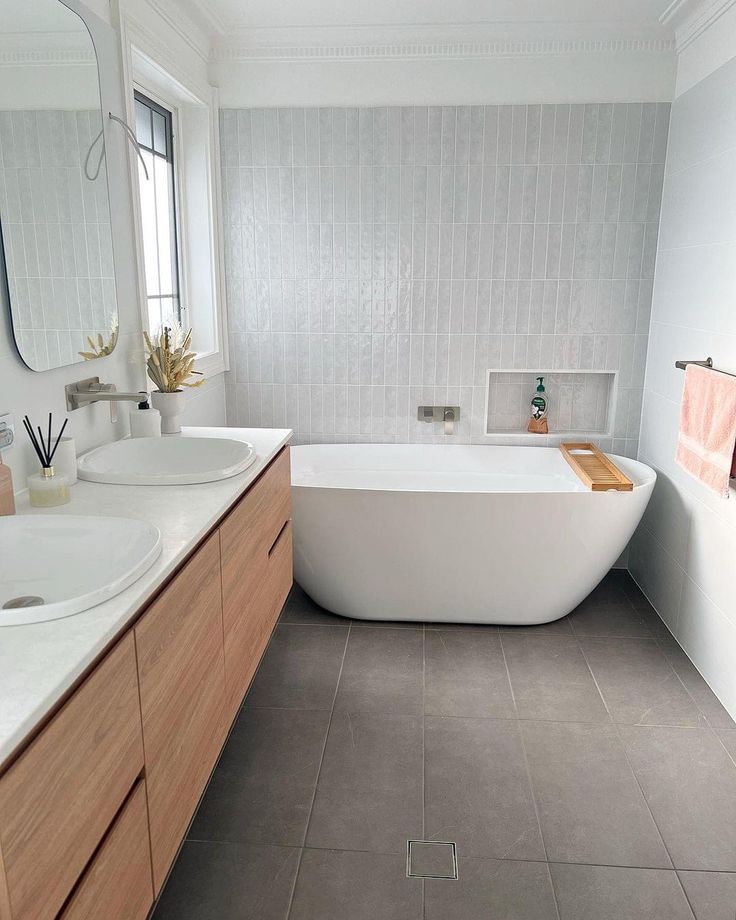 a white bath tub sitting next to two sinks in a bathroom