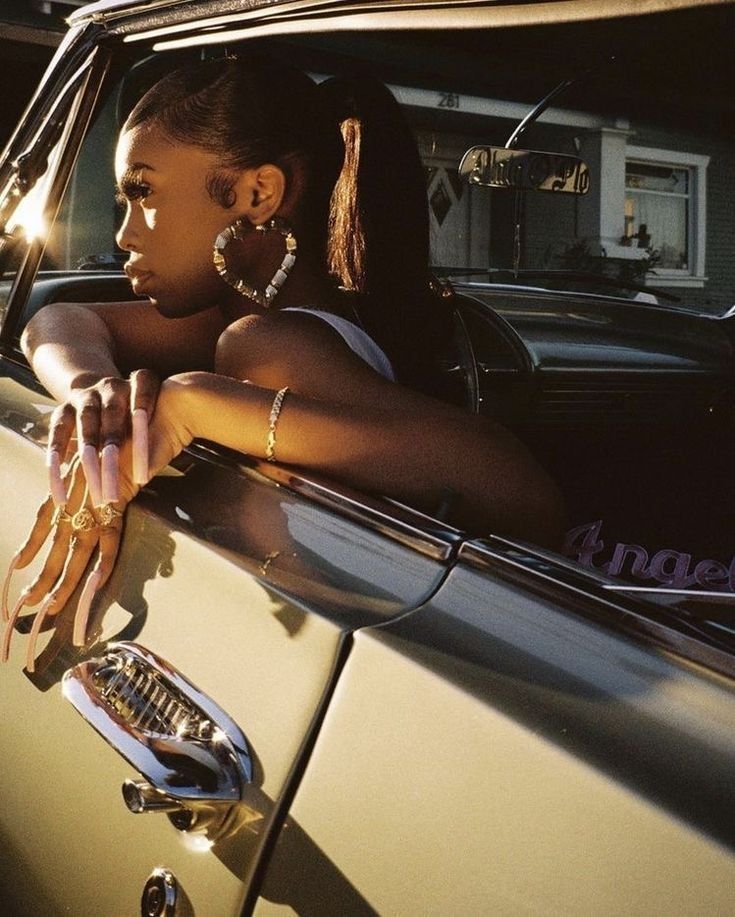 a woman leaning out the window of a car with her hand on the door handle