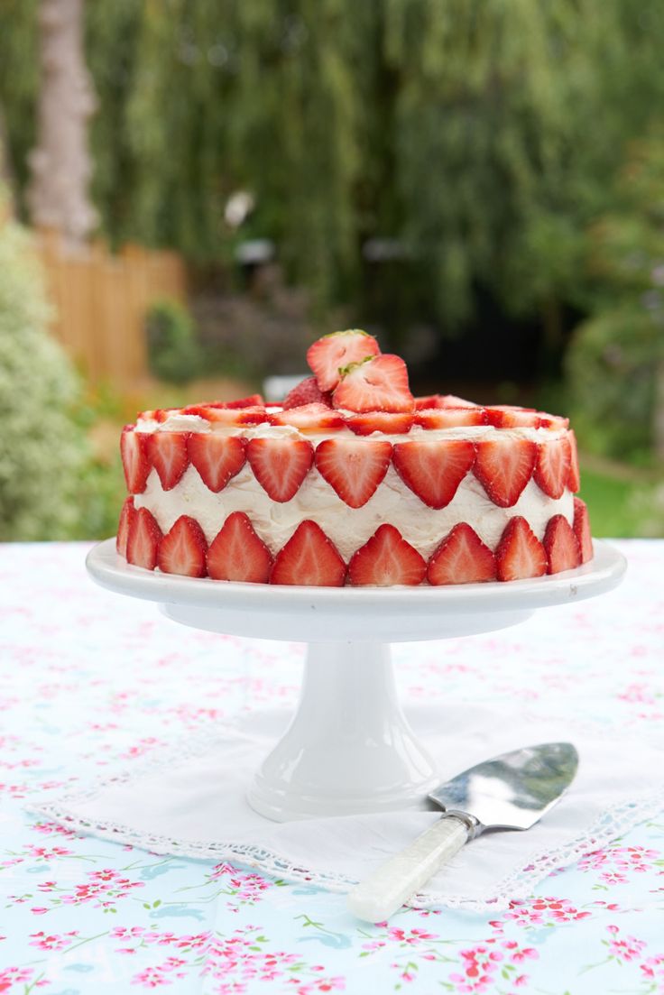 a strawberry cake with white icing and fresh strawberries on top is ready to be eaten