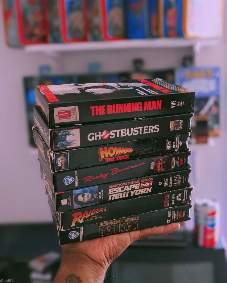 a stack of dvd's sitting on top of each other in front of a book shelf