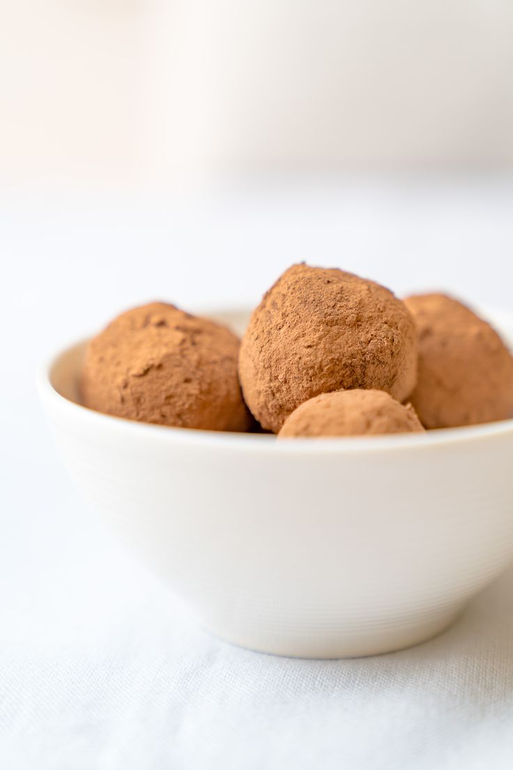 a white bowl filled with chocolate truffles on top of a table