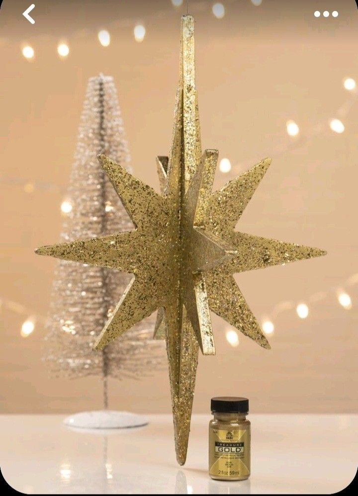 a gold glittered star ornament next to a small christmas tree