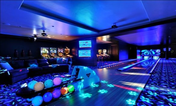 a bowling alley is lit up with blue lights and colorful balls on the floor in front of it