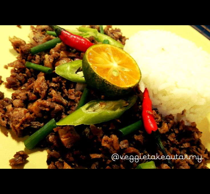 a yellow plate topped with rice, meat and veggies next to a slice of orange