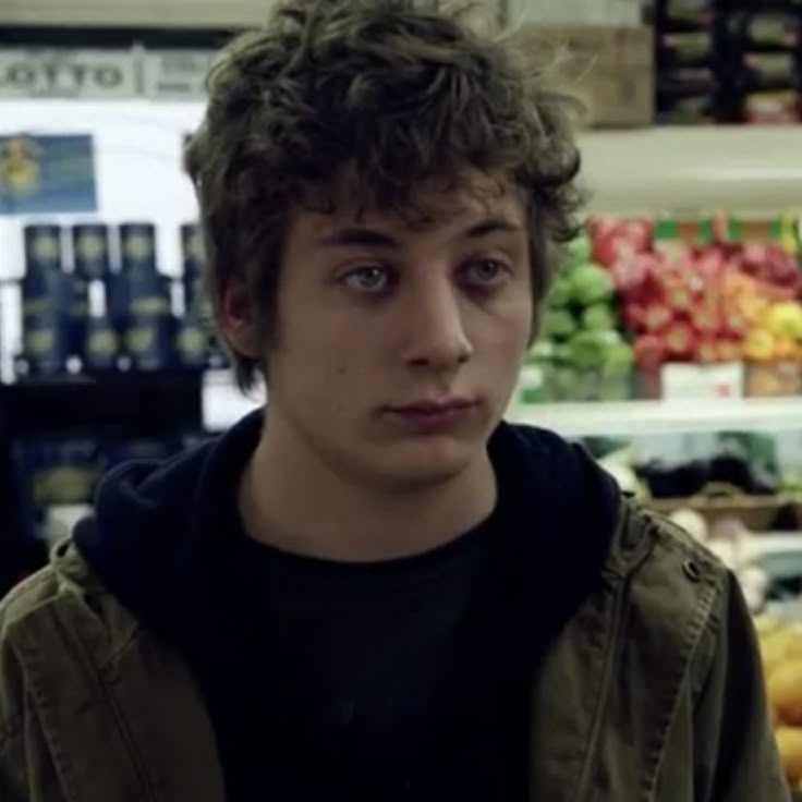 a young man in a grocery store looking at the camera with an intense look on his face