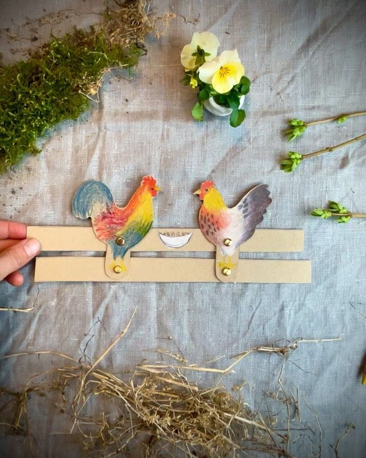 two small birds are sitting on a piece of paper next to some flowers and straw