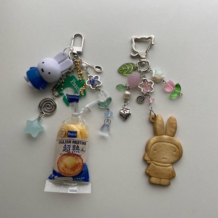 two key chains with charms on them sitting next to each other in front of a bag