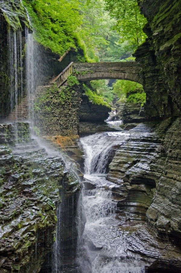 a waterfall with a stone bridge over it