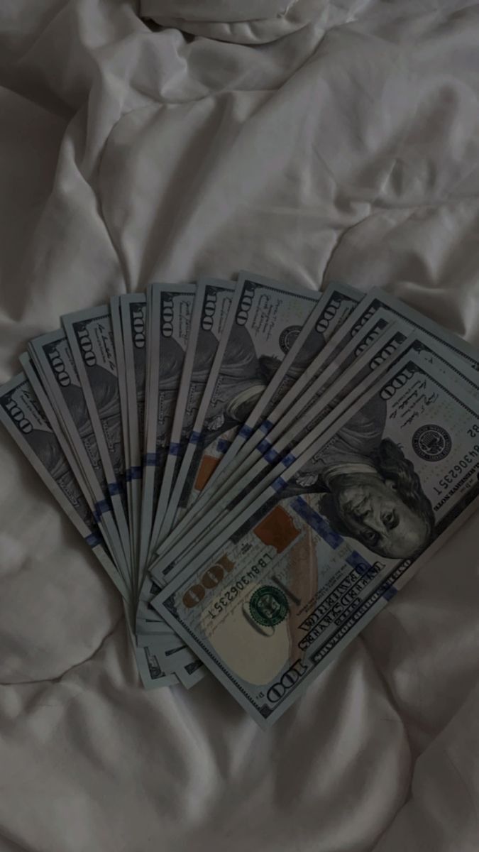 five hundred dollar bills laid out on top of a white bed sheet, with the sheets pulled down