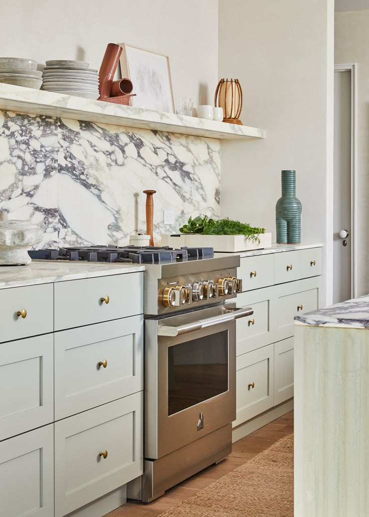 a stove top oven sitting inside of a kitchen next to white cabinets and counter tops