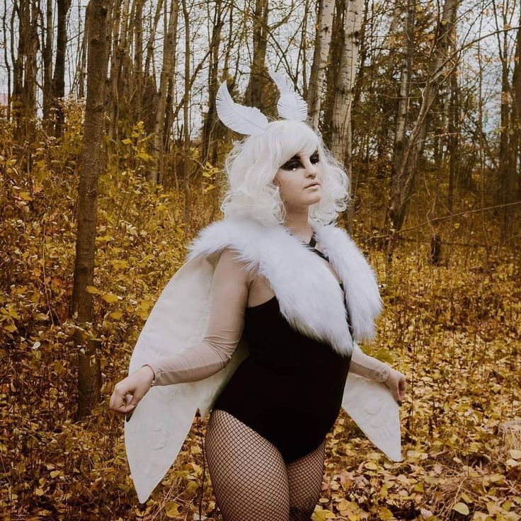 a woman in a bodysuit and white fur coat posing for the camera with her hands on her hips