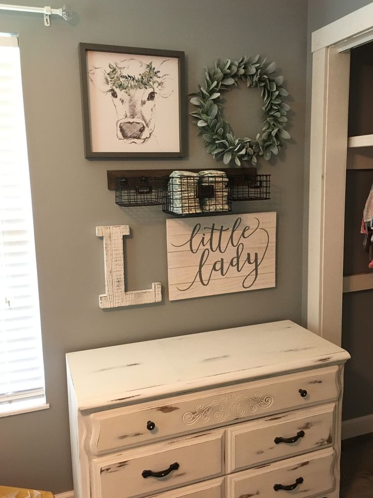 a white dresser sitting next to a wall with pictures on the wall and other items hanging above it