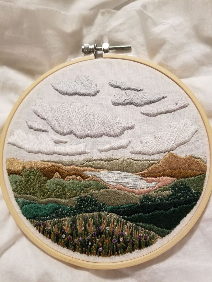 an embroidered landscape is displayed on a white sheet