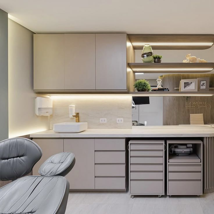 a modern kitchen with grey cabinets and white counter tops, along with an office chair