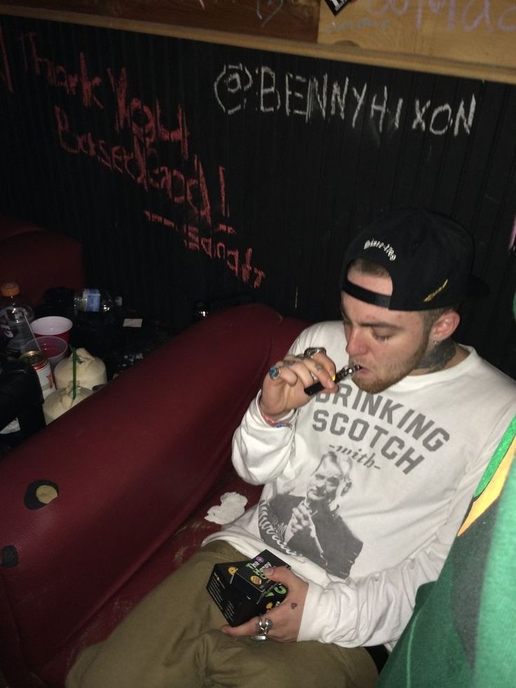 a man sitting on top of a red couch next to a blackboard with writing on it