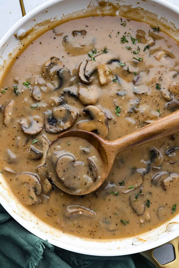 a wooden spoon sitting in a bowl filled with mushroom soup on top of a table