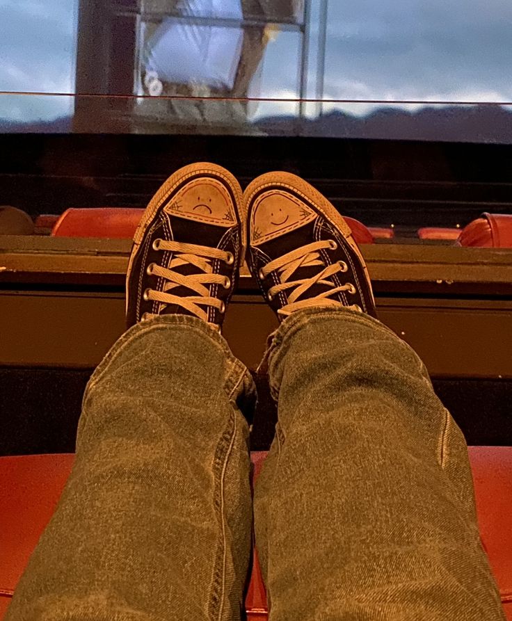 a person's feet with sneakers on in front of a television screen and chair