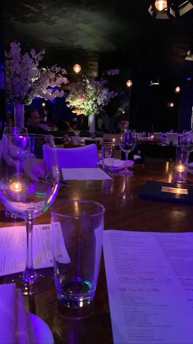 a table with wine glasses and menus on it at a fancy restaurant in the evening