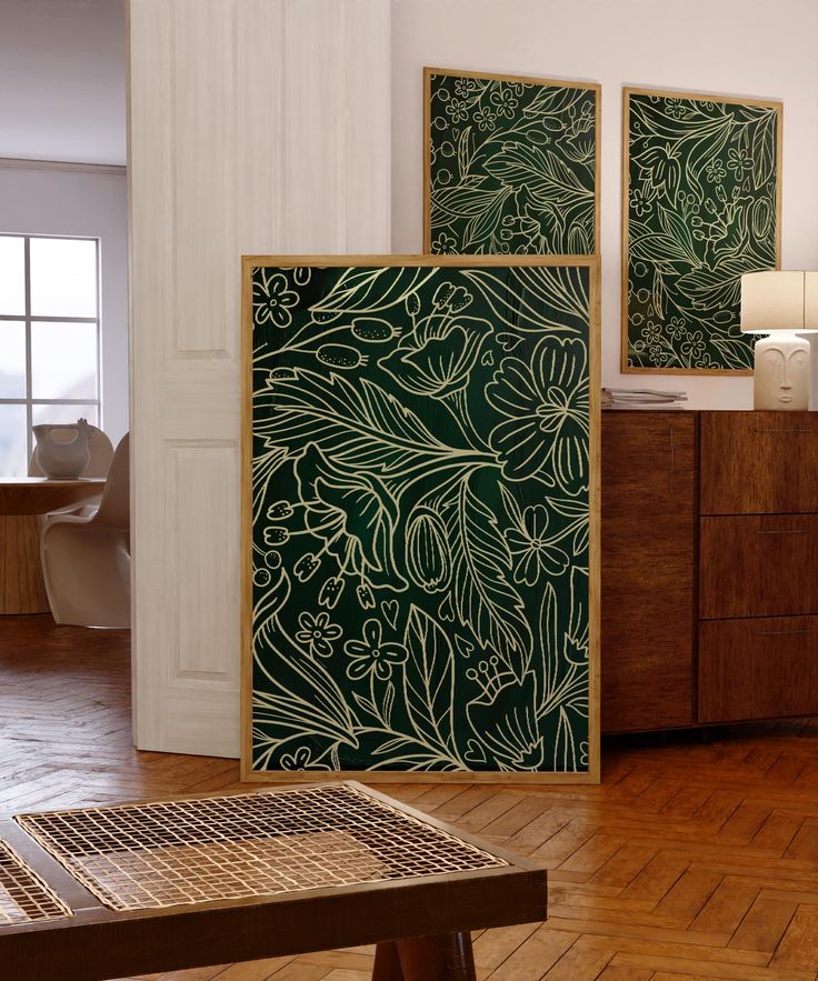 a living room with wooden floors and green art on the wall next to a coffee table