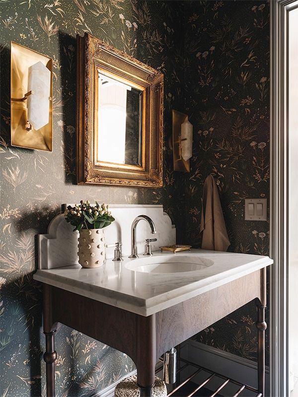 a bathroom sink sitting under a mirror next to a wall mounted faucet with flowers on it