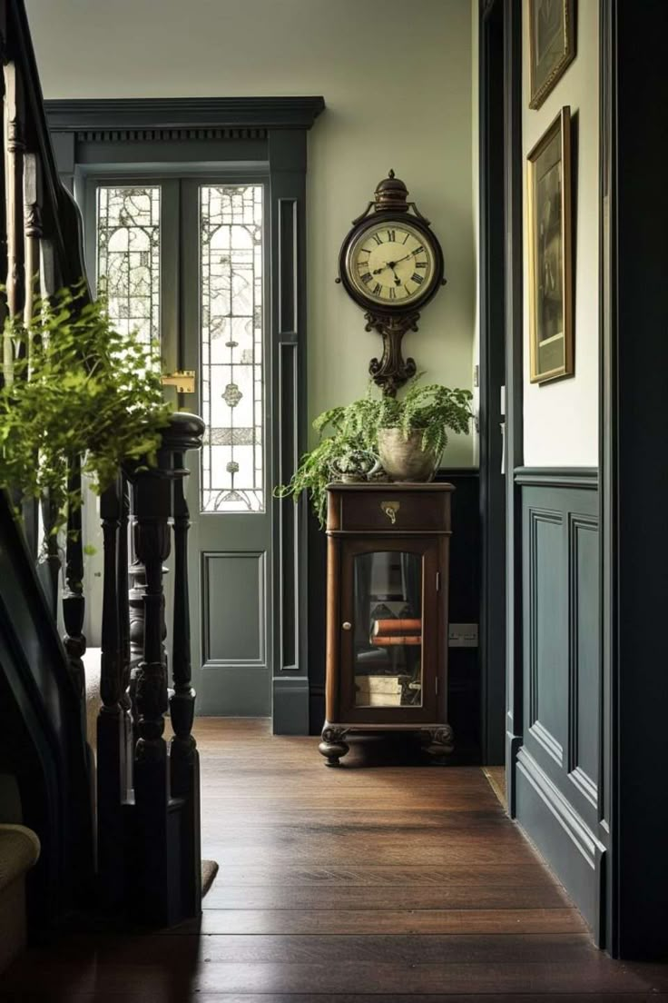 a clock is on the wall next to a wooden table with plants in front of it