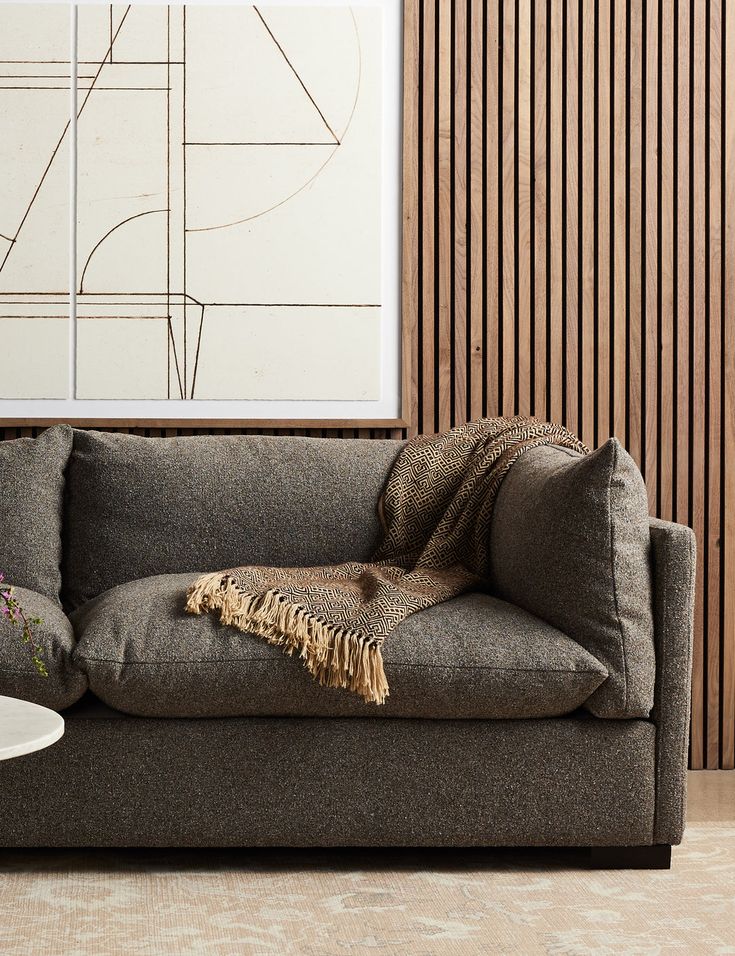 a couch with a blanket on top of it next to a table and vases