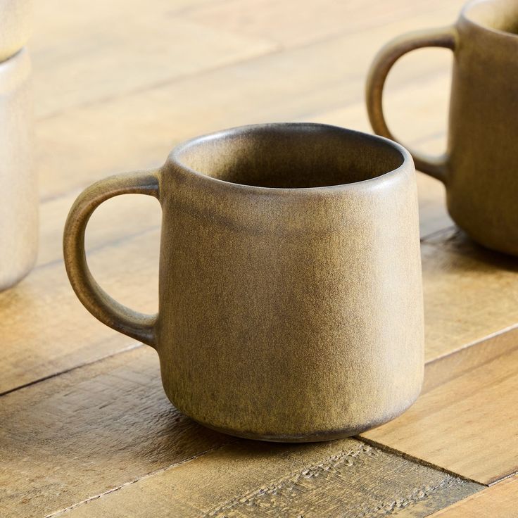 two coffee mugs sitting on top of a wooden table next to eachother