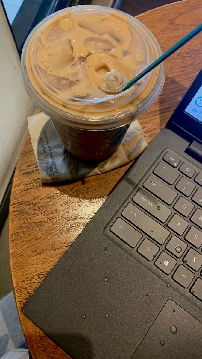 an open laptop computer sitting on top of a wooden table next to a cup of coffee