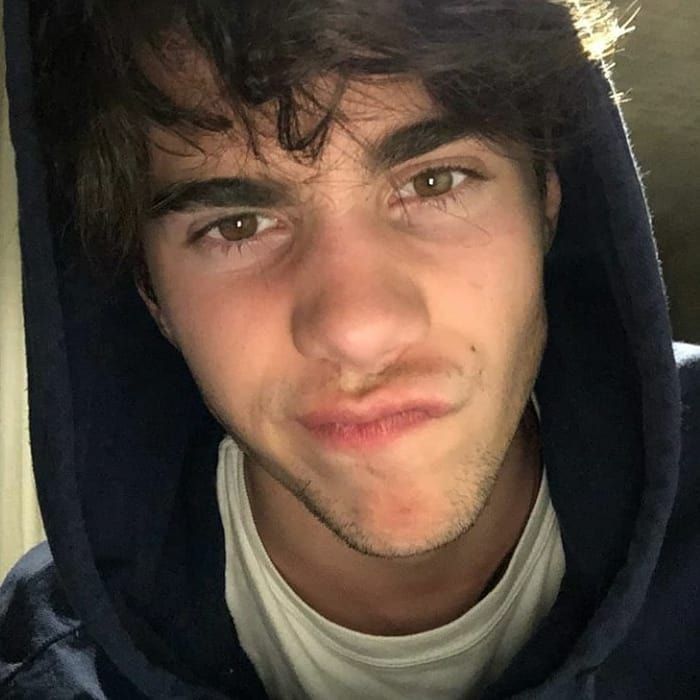 a young man wearing a hoodie looking at the camera with an intense look on his face