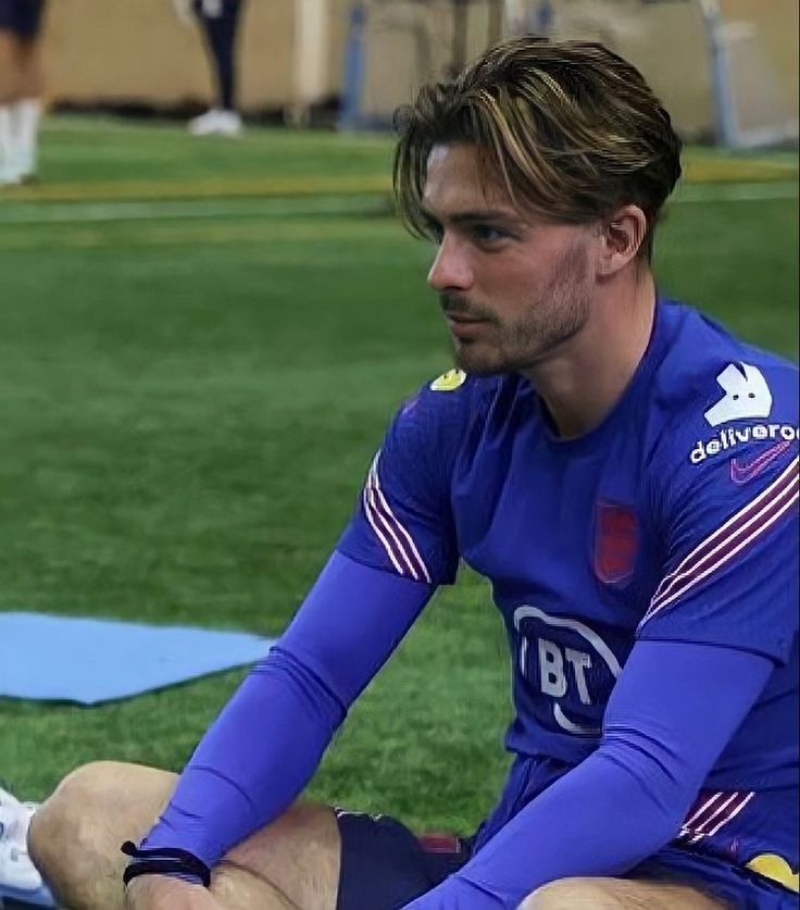 a man sitting on top of a field next to a soccer ball