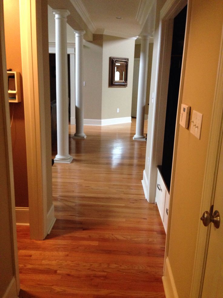 an empty hallway leading to another room with wood floors and columns on either side of the door