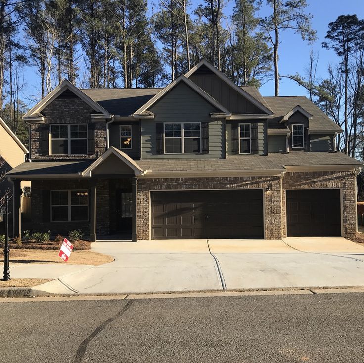 a large house with two garages in front of it and trees on the other side