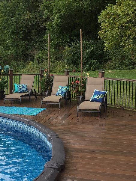 a deck with chairs next to a swimming pool