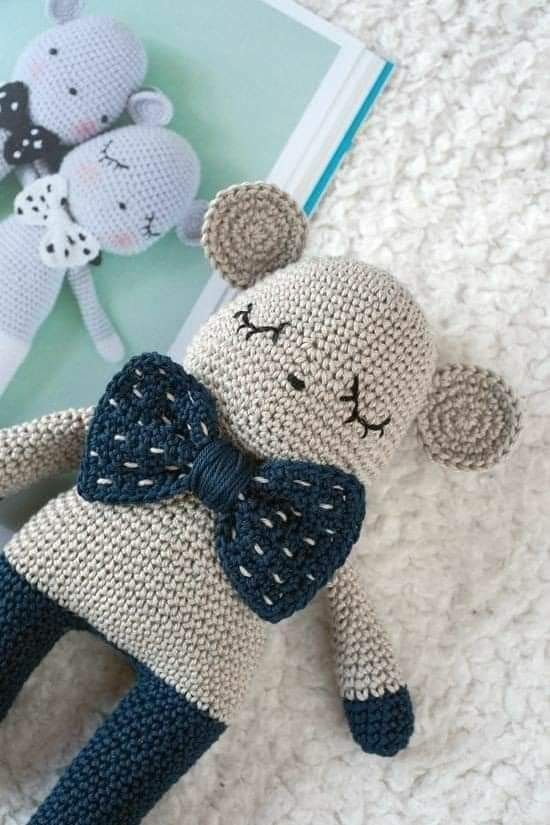 a crocheted stuffed animal with a bow on it's head laying next to a book