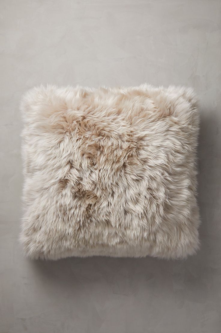 a white furry pillow sitting on top of a wall