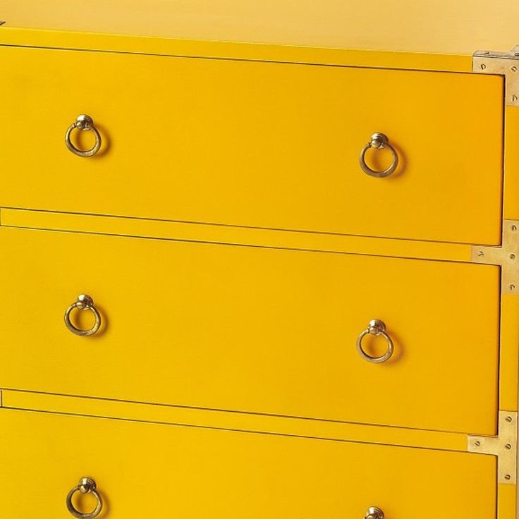 a yellow chest of drawers with metal handles