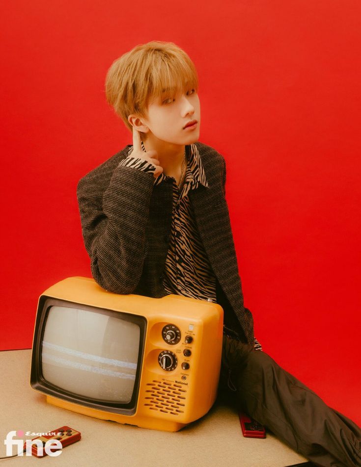 a young man sitting on top of a yellow tv with his hand on his face