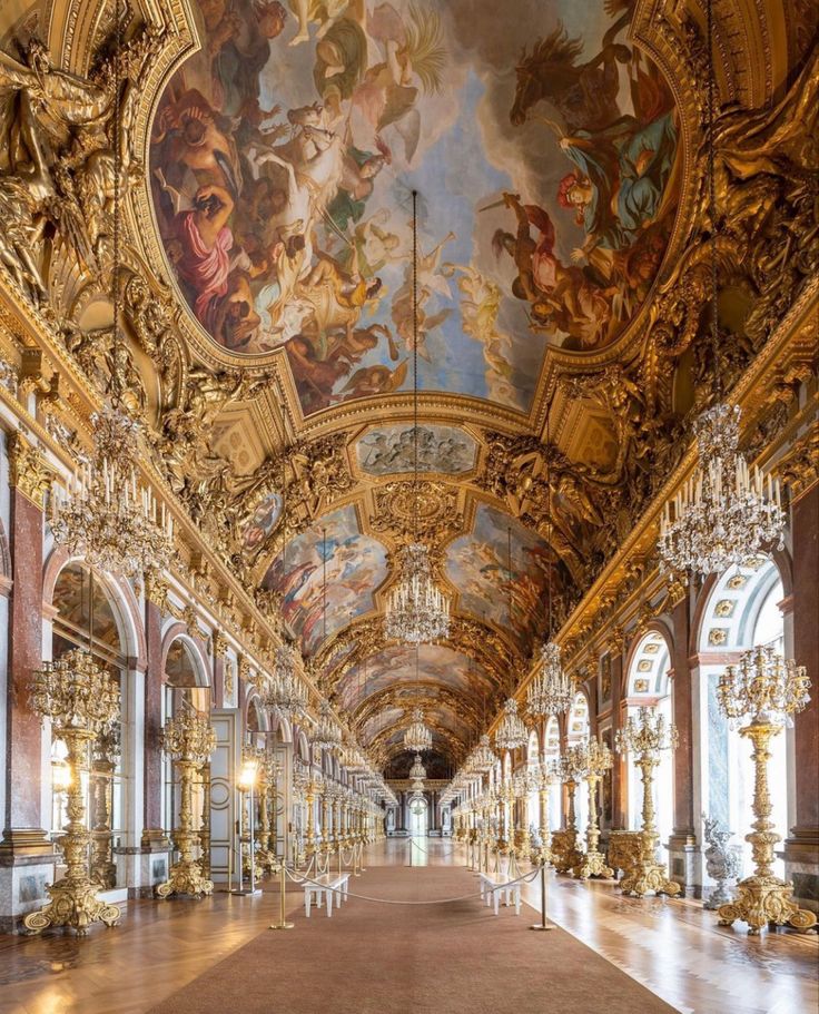 an ornately decorated hall with chandeliers and paintings on the ceiling is shown