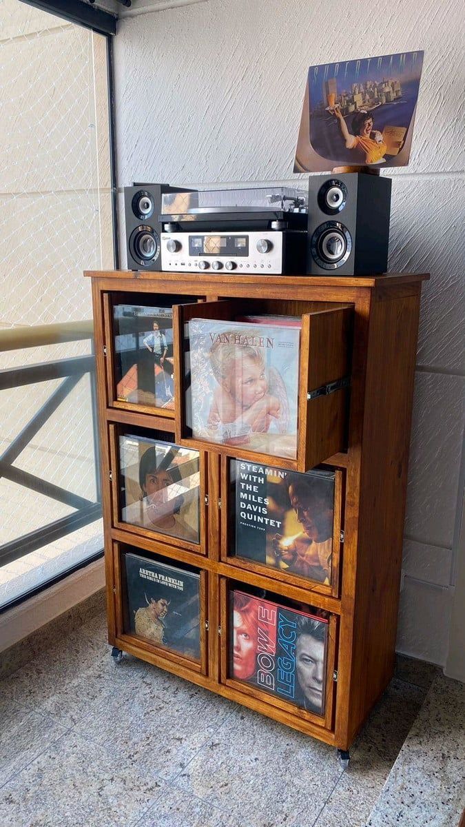 an old record player is sitting on top of a wooden cabinet with cd's in it