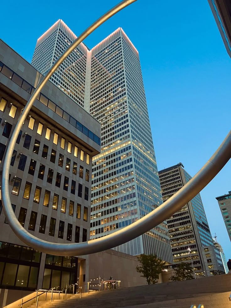 a large metal sculpture in front of some tall buildings