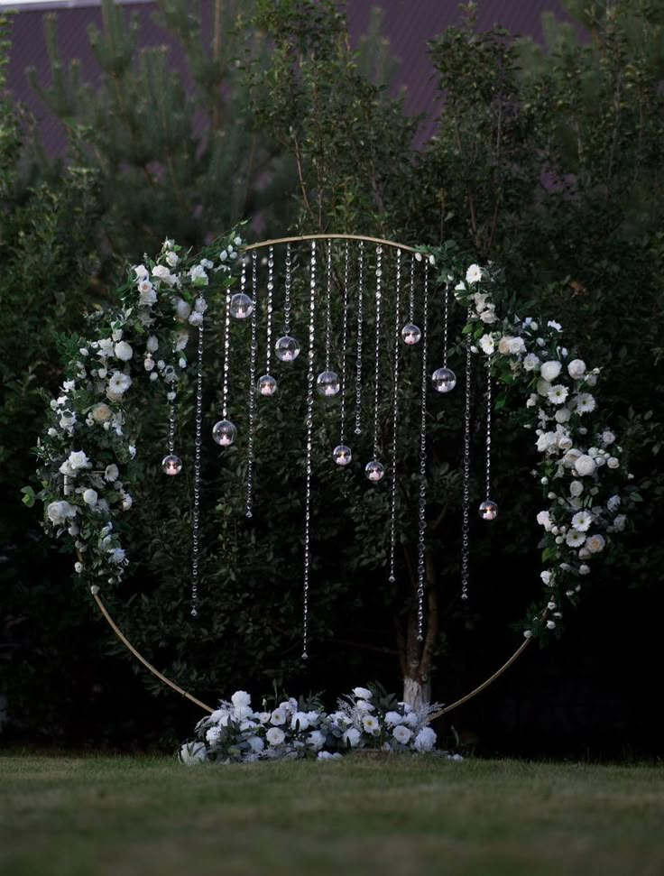 a wedding arch with flowers and pearls hanging from it