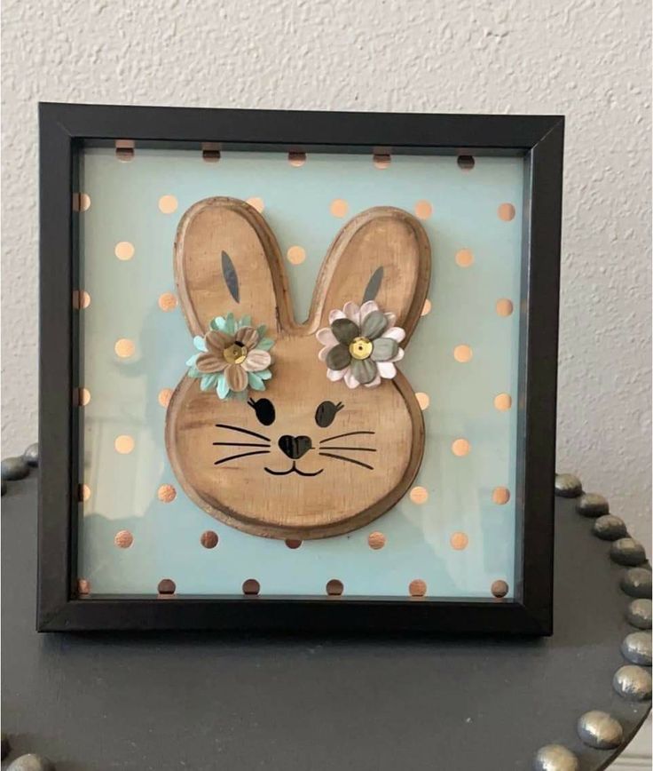 a wooden bunny with flowers on it's head and polka dots in the background