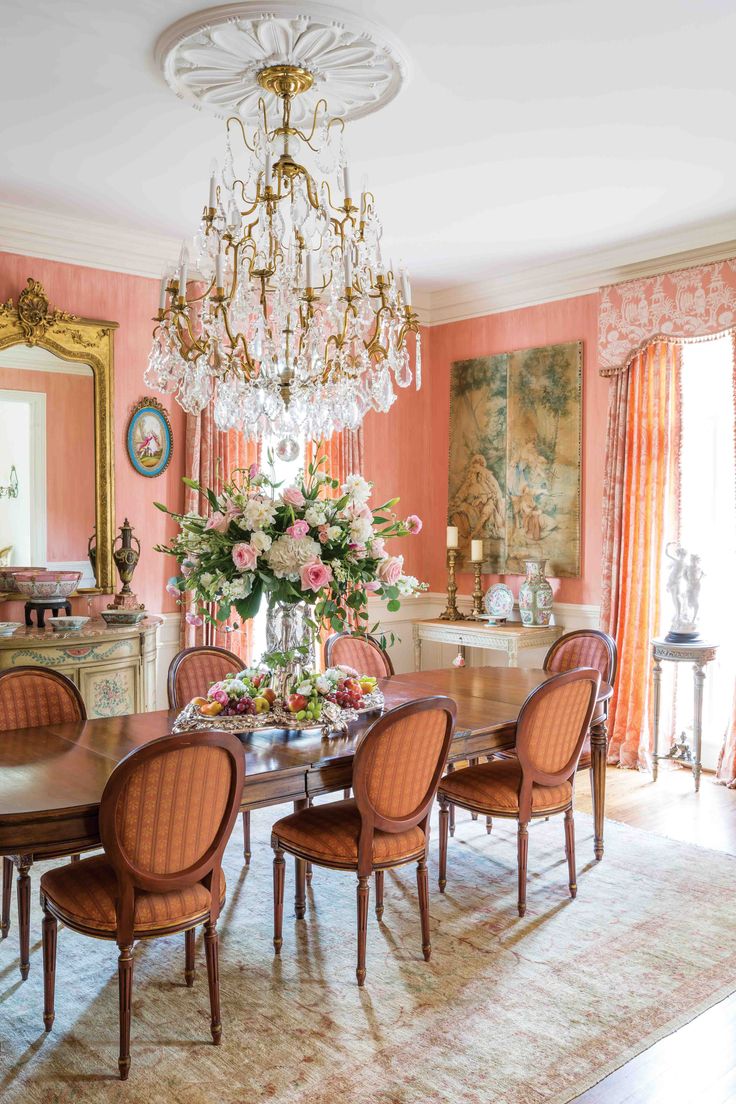 an elegant dining room with pink walls and chandelier