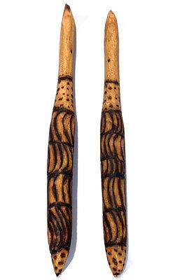 two wooden paddles with designs on them sitting side by side against a white background