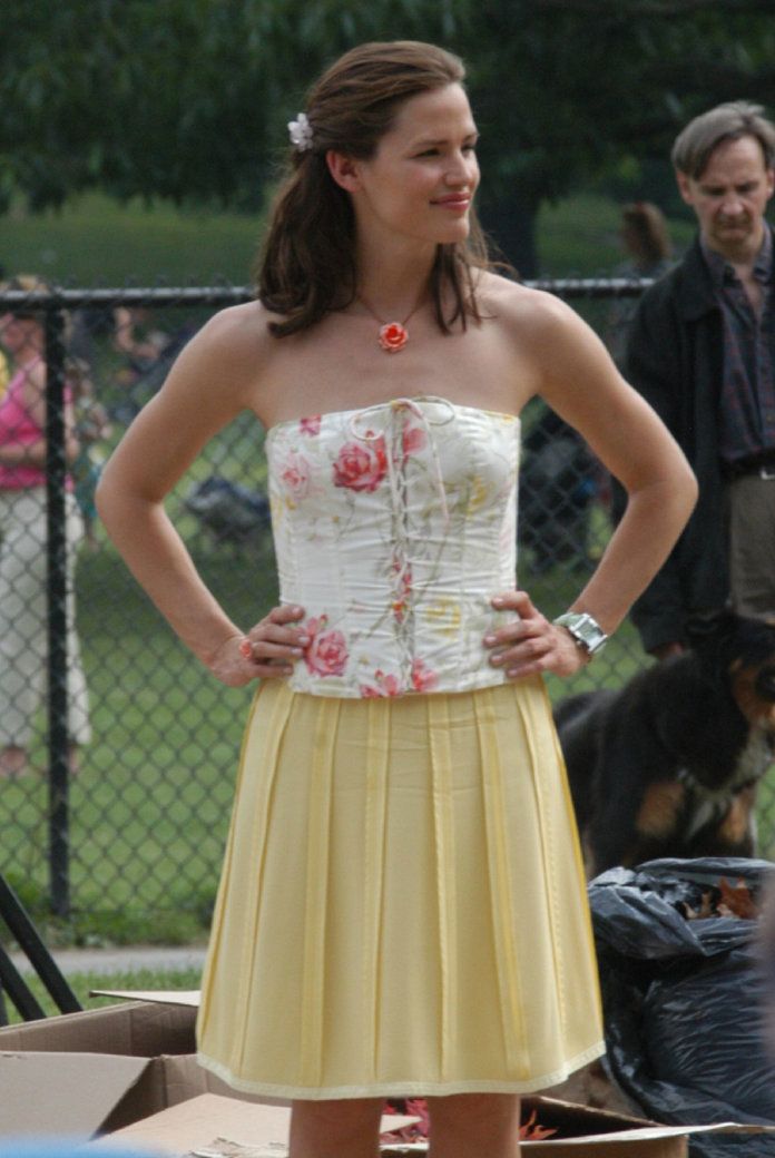 a woman in a yellow dress standing next to a dog