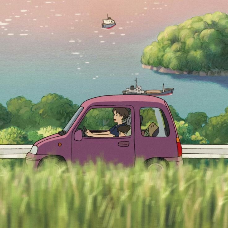 a car driving down a road next to a lush green field filled with tall grass