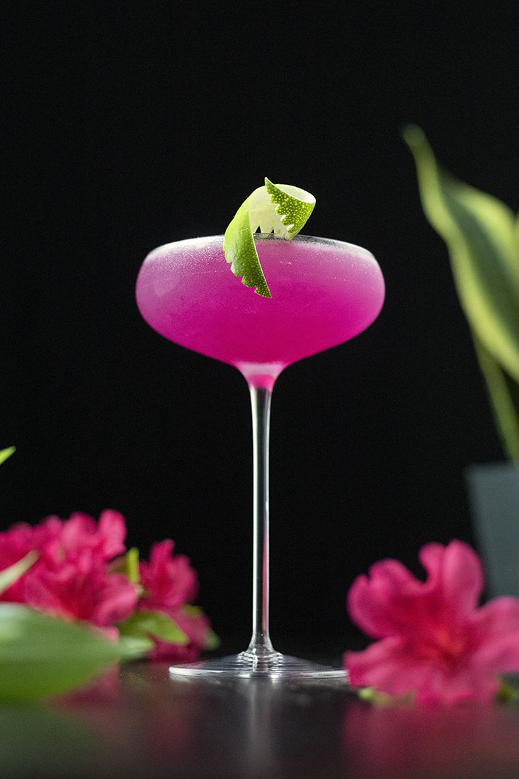 a pink cocktail with a green garnish on the rim